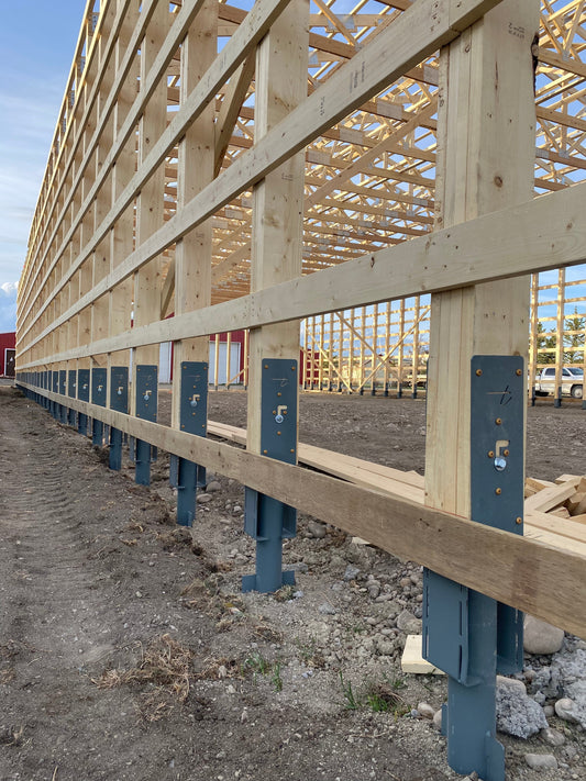 Steel post foundation system for post-frame building construction